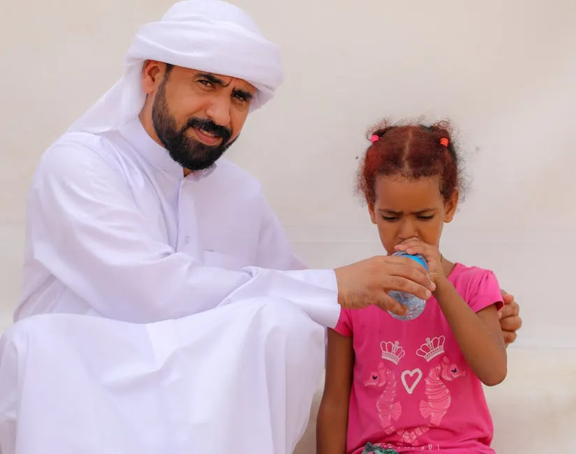 Man assists child with drinking water outdoors