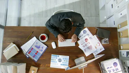 Horizontal video: A man using his computer to record the data on the documents on his desk 3195532. Duration: 19 seconds. Resolution: 3840x2160