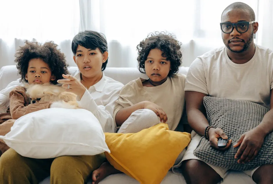 Multiethnic family watching TV with dog on sofa