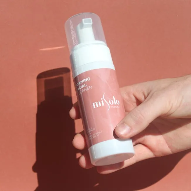 Person Holding a Bottle of Facial Cleanser
