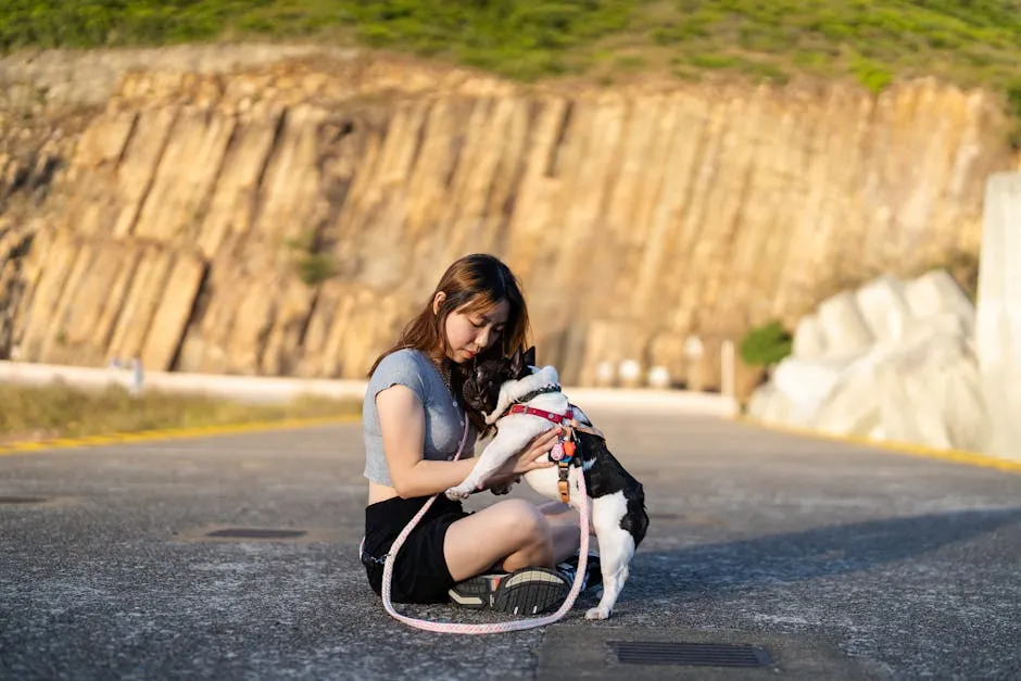 A Girl Sitting on the Ground and Holding Her French Bulldog