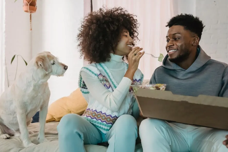 Black cheerful couple enjoying fresh salad together while dog watching