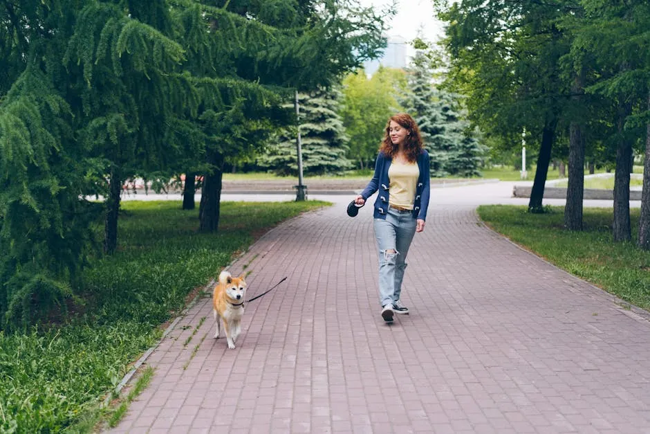 A woman enjoys a leisurely walk with her Shiba Inu in a scenic park pathway.