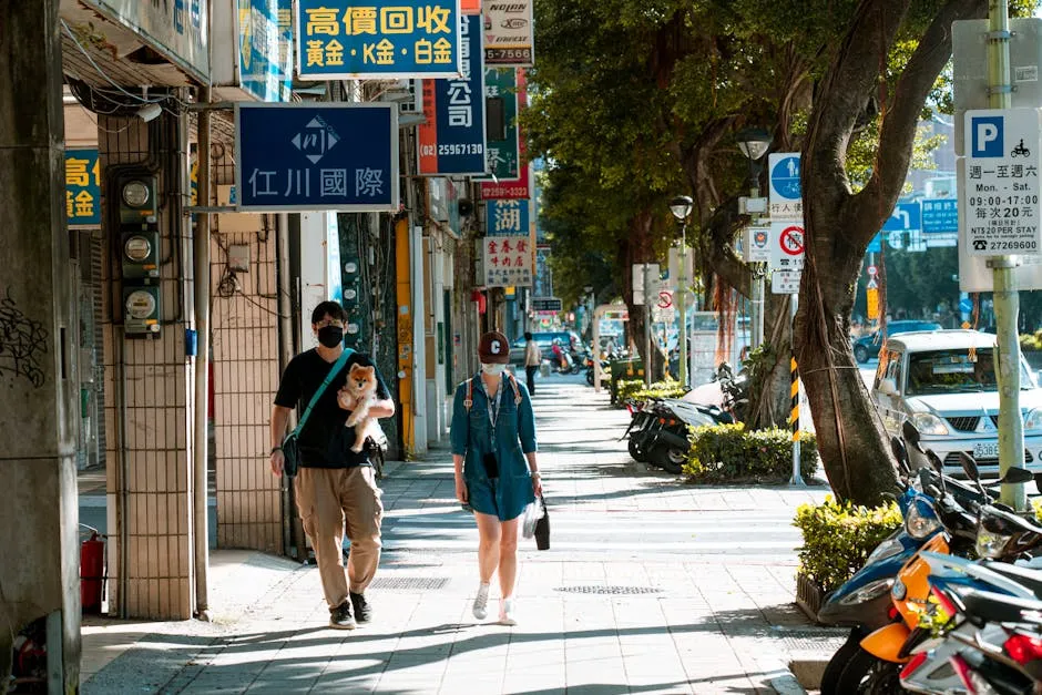 Man in a Black Shirt Walking on a Sidewalk while Carrying a Dog