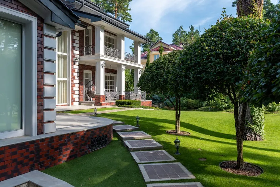 Modern house near backyard with path near green grass and plants with trees under blue sky in summer sunny day