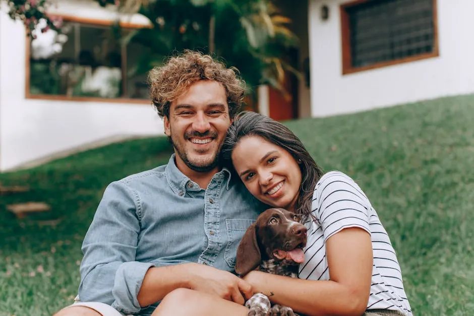 A joyful couple sitting on grass with their dog, enjoying a sunny day outdoors.