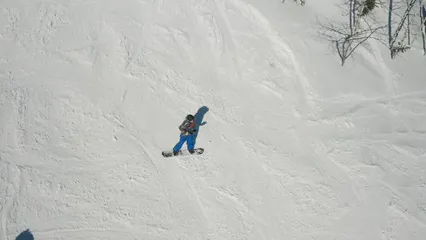 Horizontal video: Drone footage of a person snowboarding downhill 8419139. Duration: 31 seconds. Resolution: 2688x1512