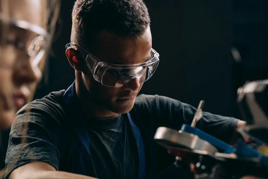 Close-up of a technician concentrating on work, wearing safety glasses in a workshop setting.