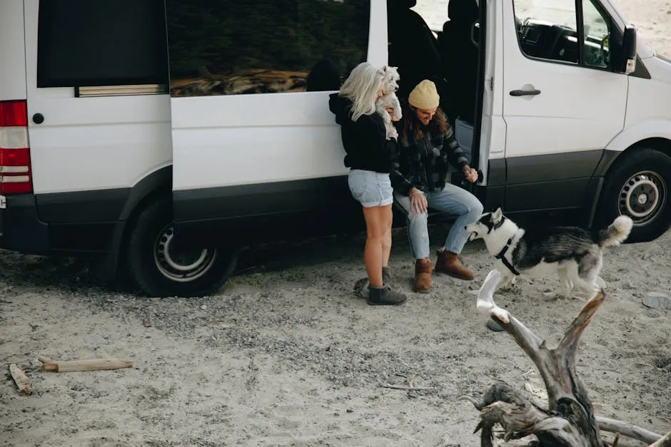 A couple enjoys travel with their dogs by camper van on a sandy beach.