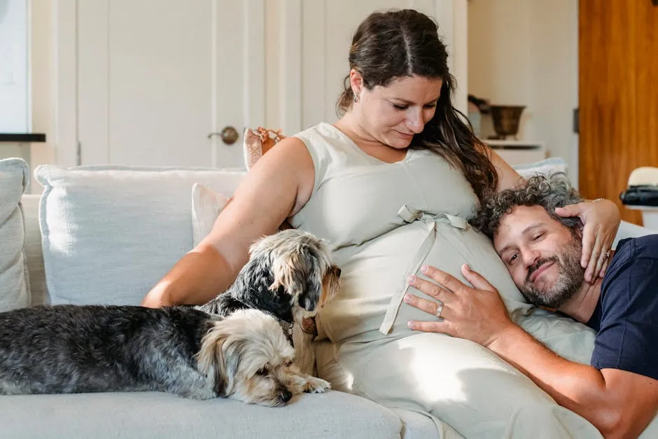 Happy pregnant couple relaxing on the couch with their dogs, sharing a tender moment indoors.