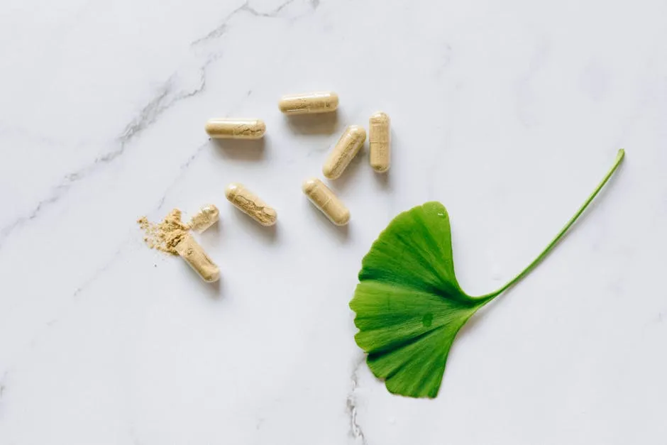 Top view of Ginkgo Biloba capsules with a leaf on a marble surface, symbolizing natural supplements.