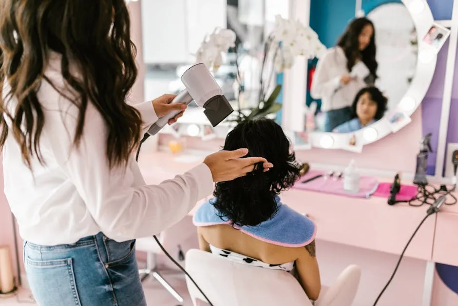 A hairstylist uses a hairdryer on a client at a modern salon with a mirror reflection.