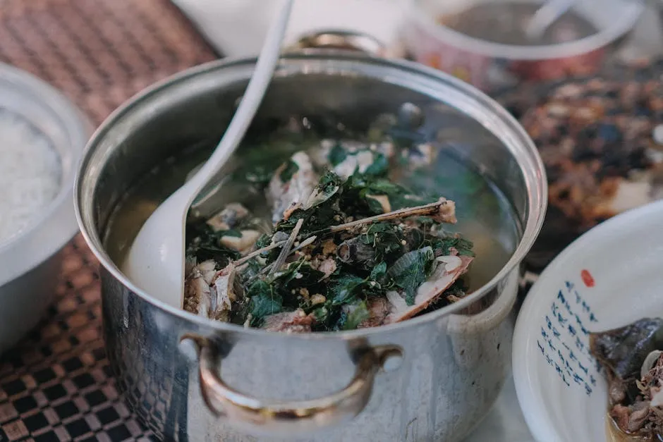 Warm homemade fish soup with fresh herbs in a stainless steel pot, ready to serve.