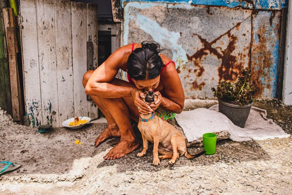 A woman lovingly kisses her dog on a rustic street. Intimate and heartwarming moment captured in an outdoor setting.