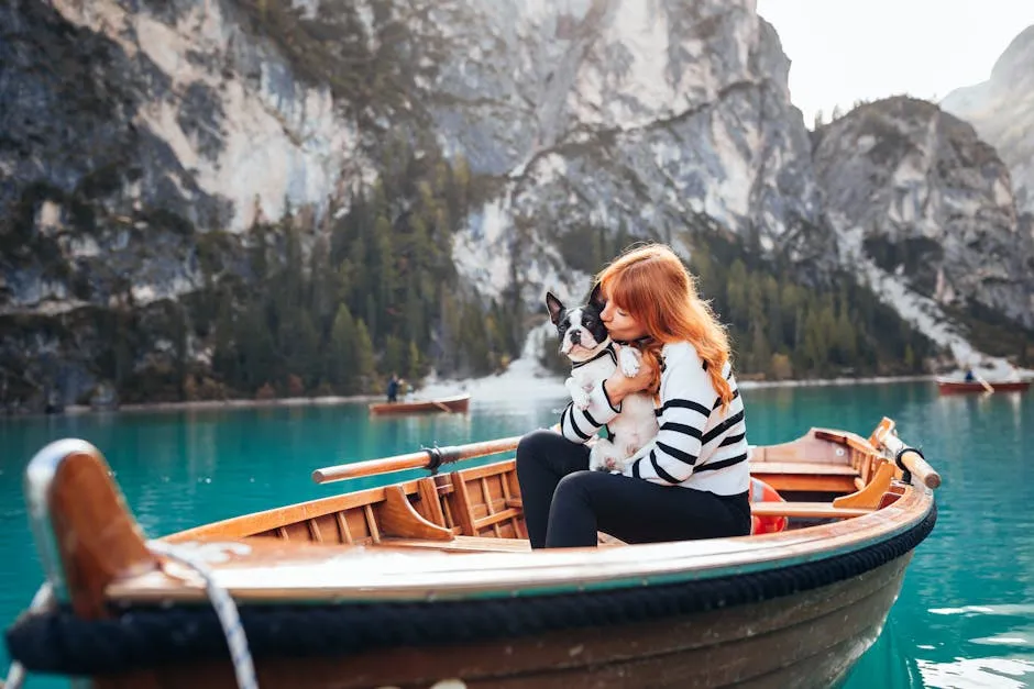 A Woman with Her Dog Sitting on a Boat on a Lake in the Mountains 